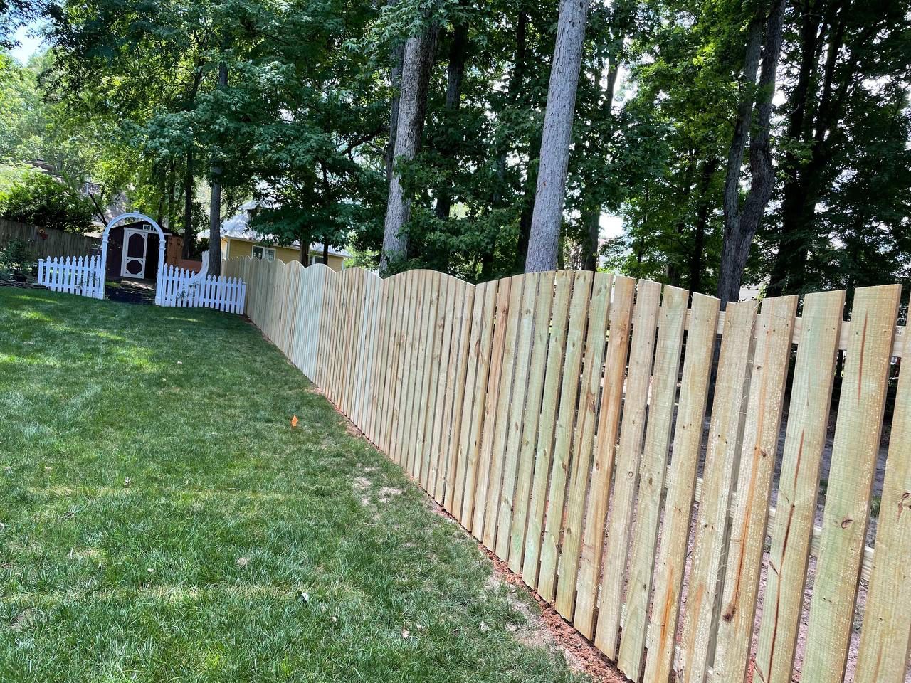 A wooden fence surrounds a lush green yard.