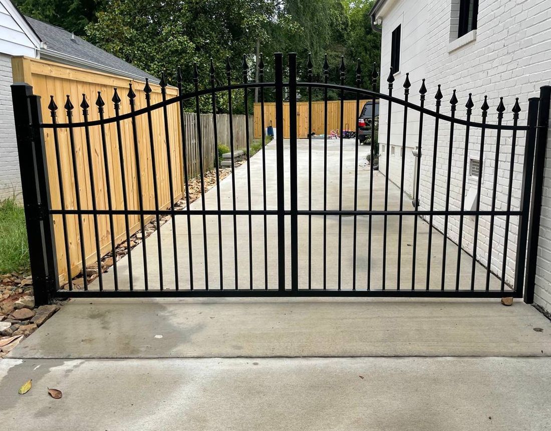 A black wrought iron gate is sitting in front of a house.
