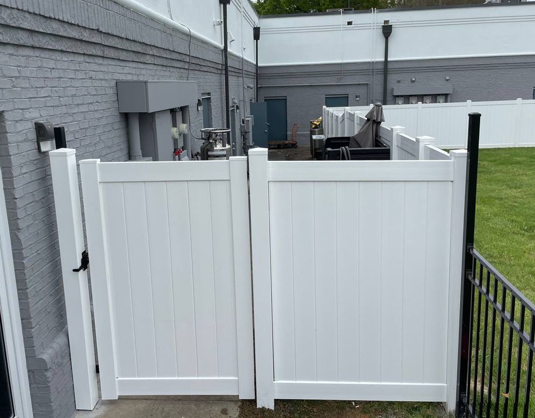 A white fence with a gate in front of a building.