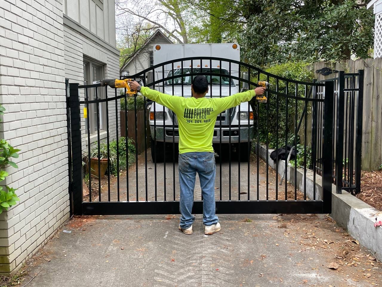 A man is standing in front of a gate with his arms outstretched.