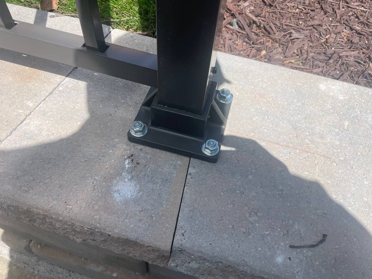 A black pole is sitting on top of a brick wall.