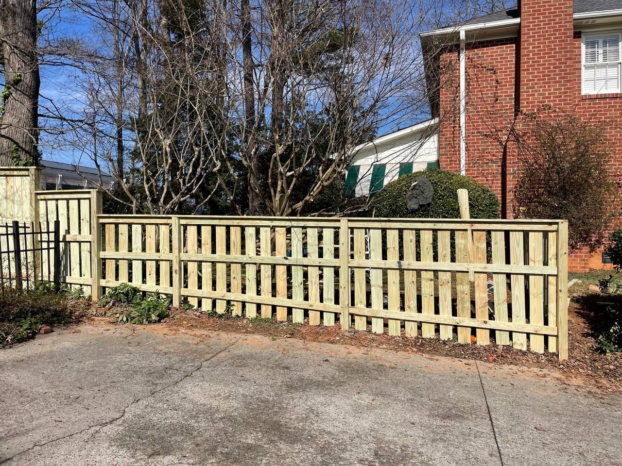 A wooden fence is sitting in front of a brick house.