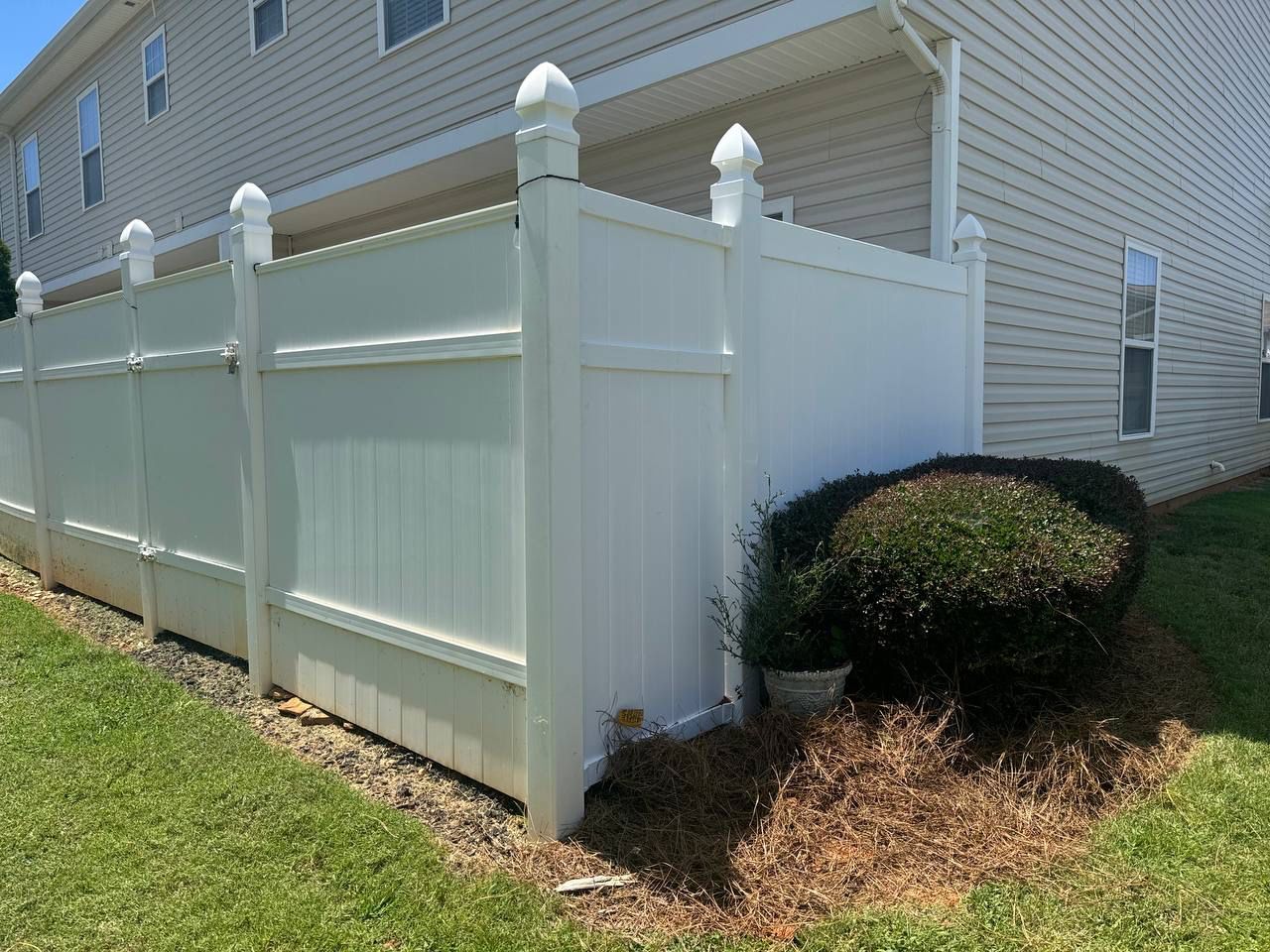 A white fence is in front of a house.