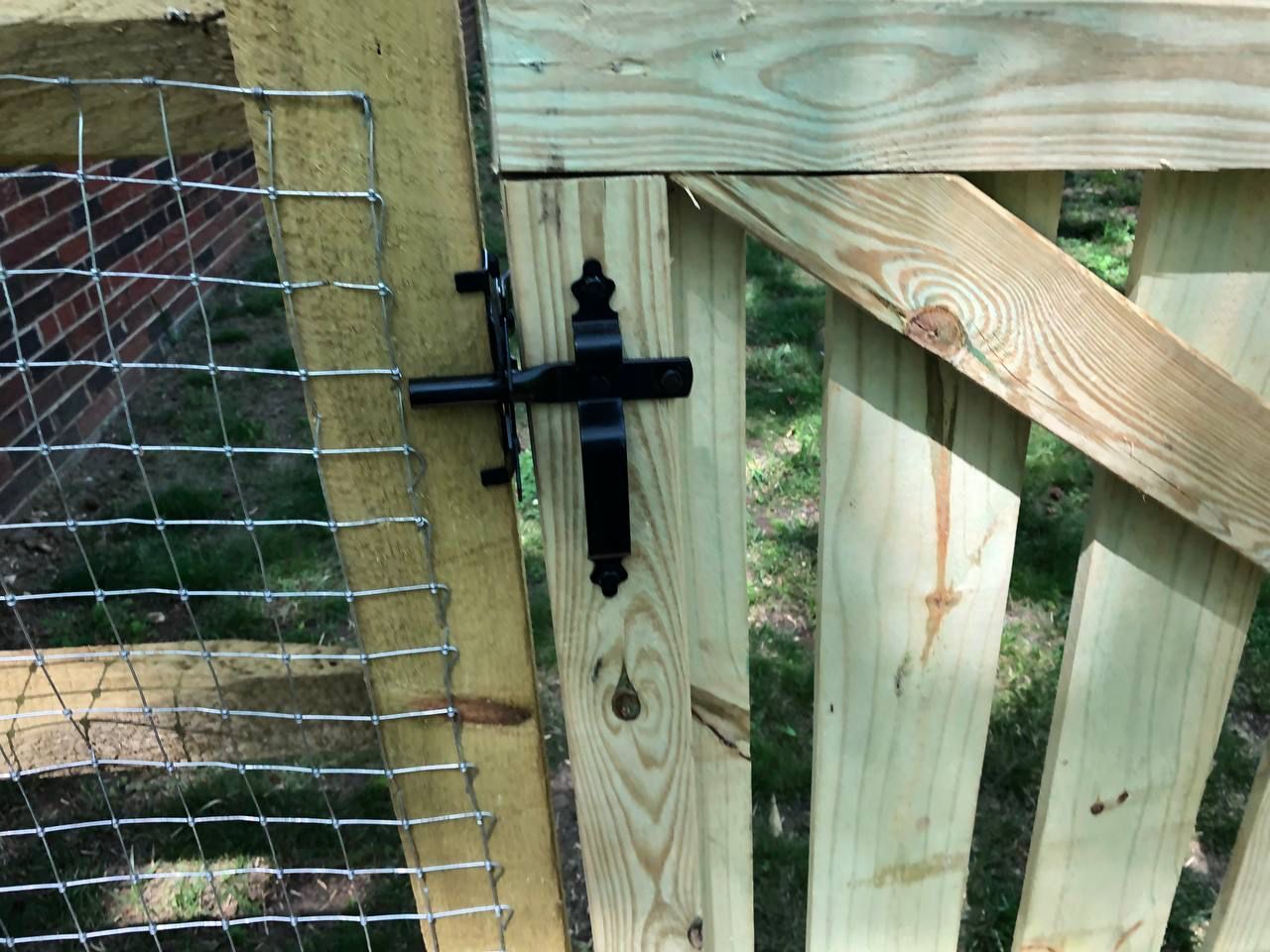 A wooden gate with a metal fence behind it