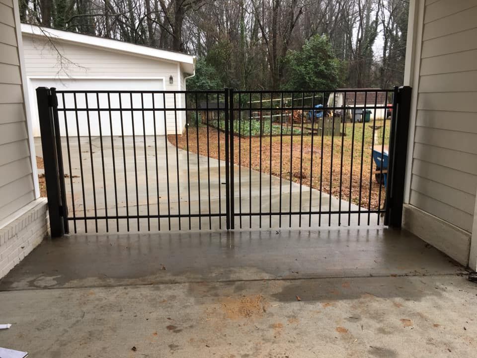 A black metal gate is sitting in front of a garage.