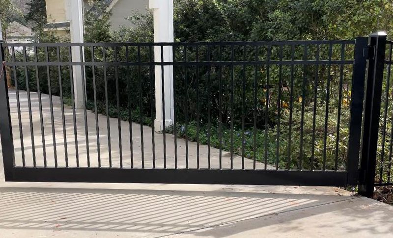 A black metal gate is open to a driveway