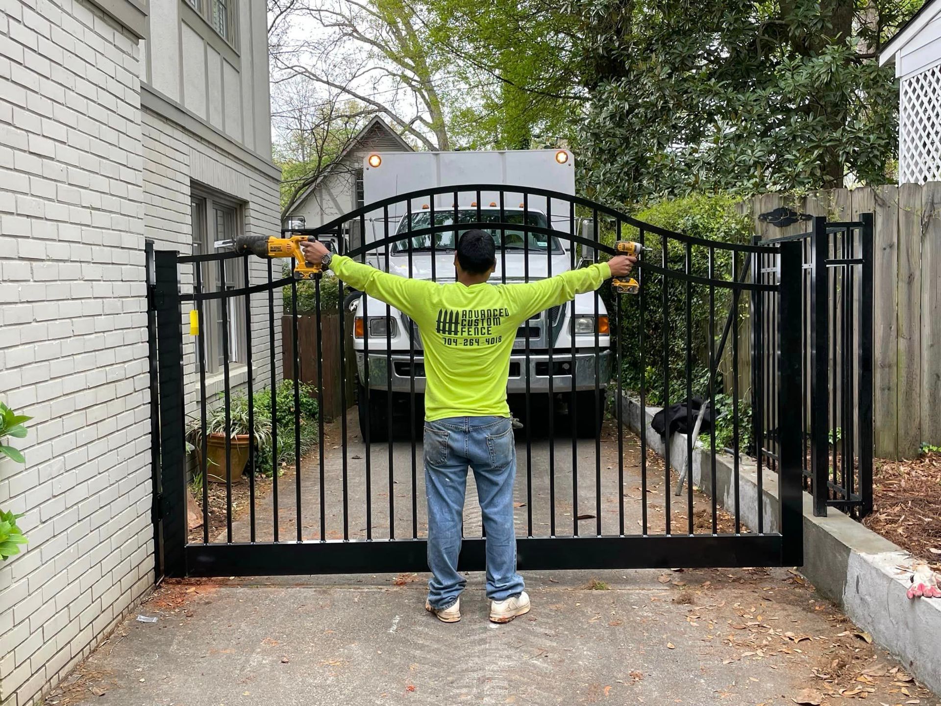 A man is standing in front of a gate with his arms outstretched.