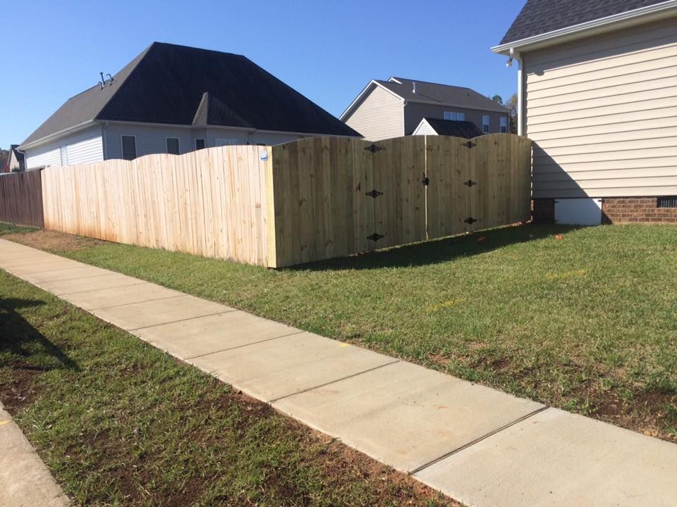 A wooden fence along a sidewalk in front of a house