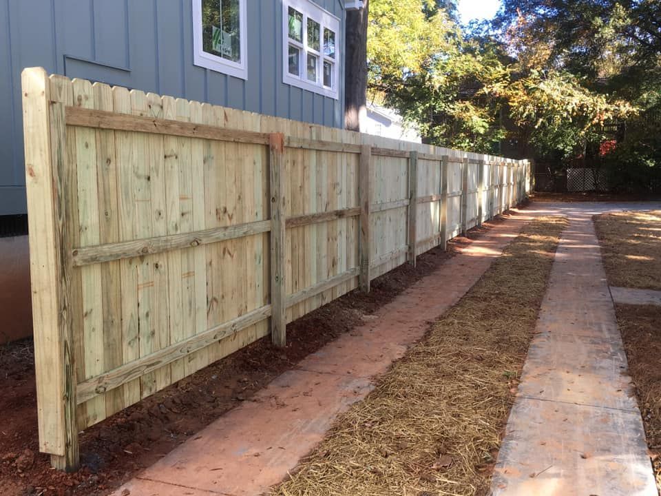 A wooden fence along a sidewalk next to a house.