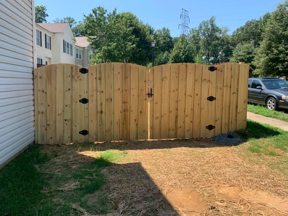 A wooden fence with a gate in the backyard of a house.