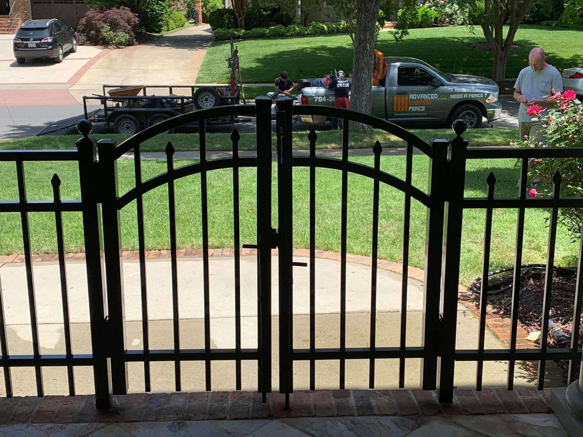 A man is standing in front of a gate with a truck in the background.