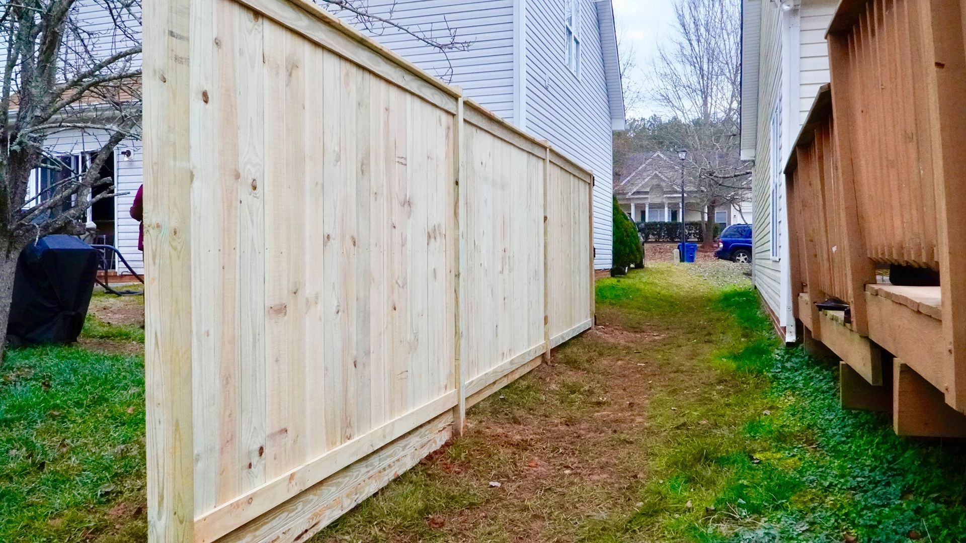 A wooden fence is in the backyard of a house.