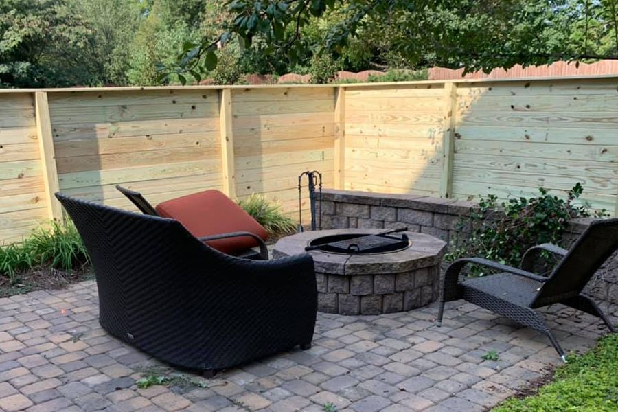 There is a fire pit in the backyard with chairs around it.