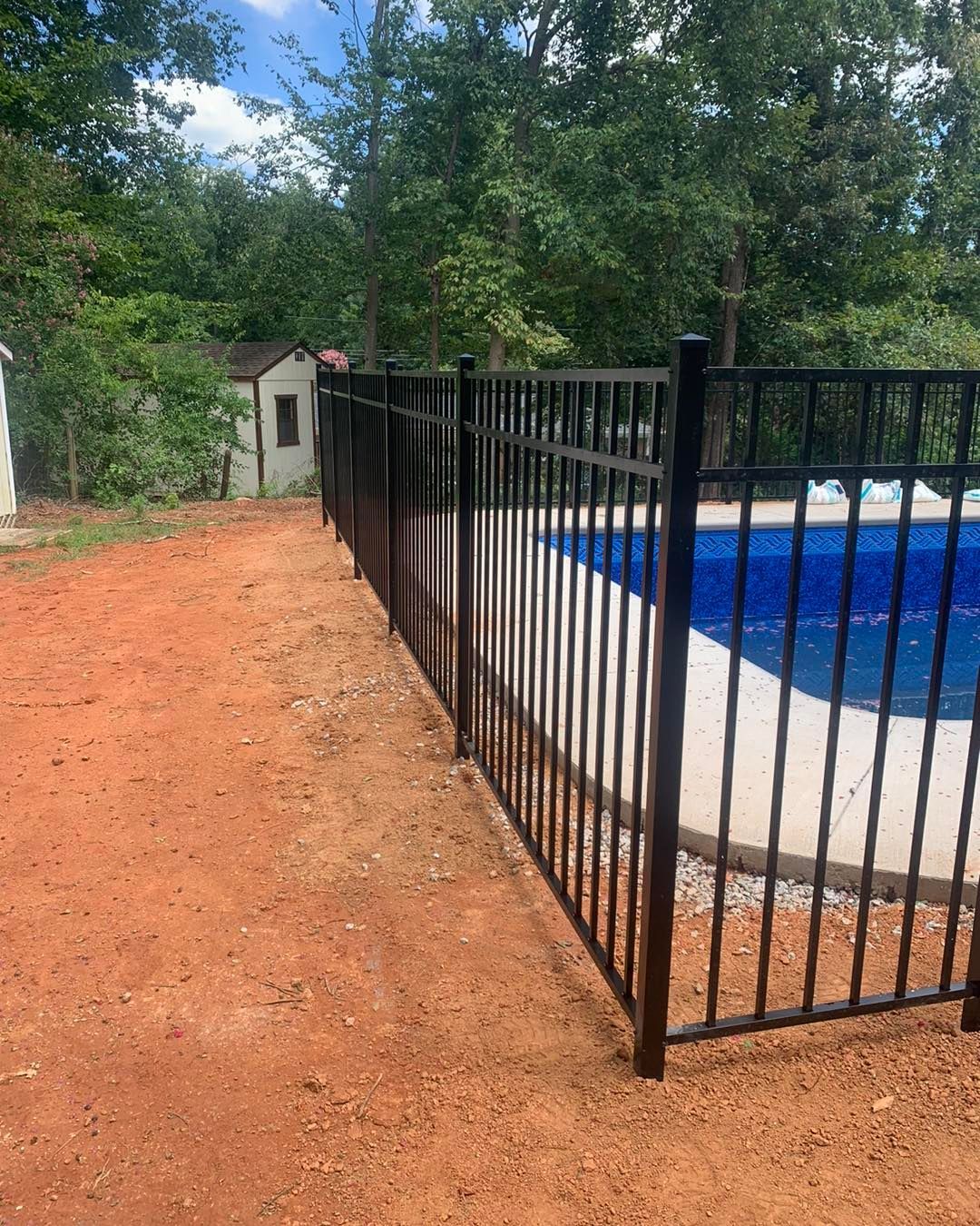 A black metal fence surrounds a swimming pool.