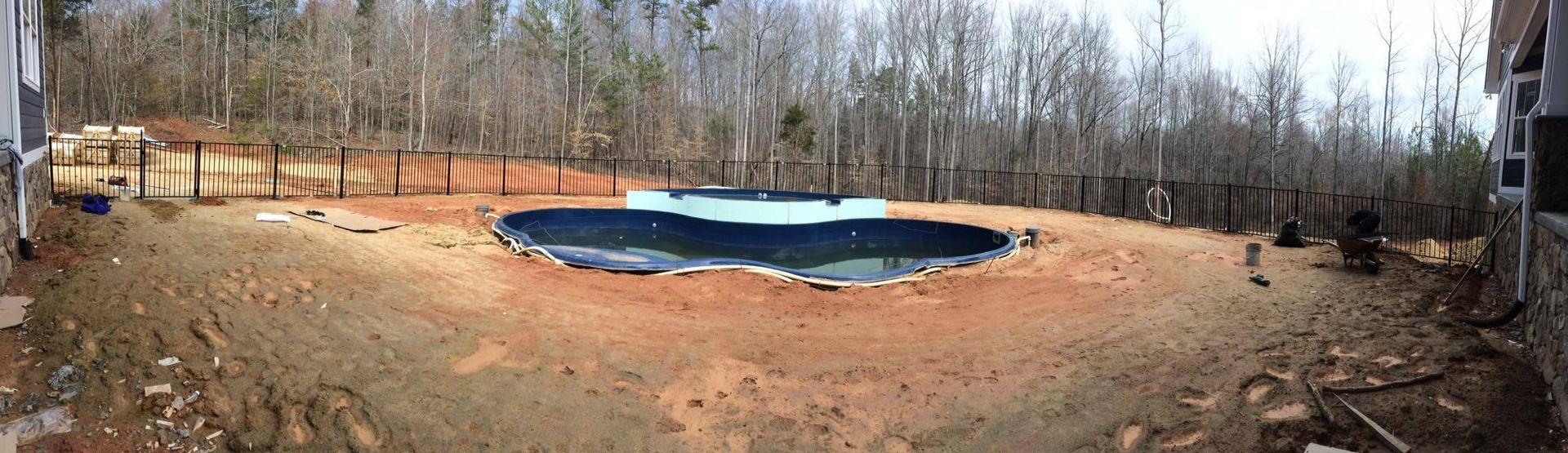 A large swimming pool is surrounded by trees in a backyard.