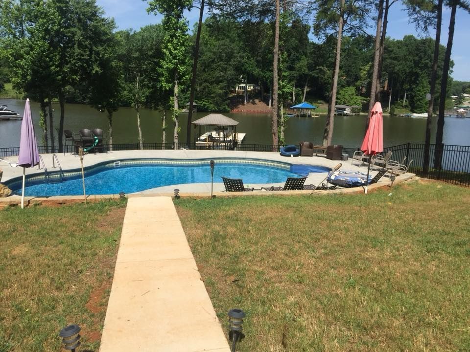 There is a large swimming pool in the middle of a lush green field.