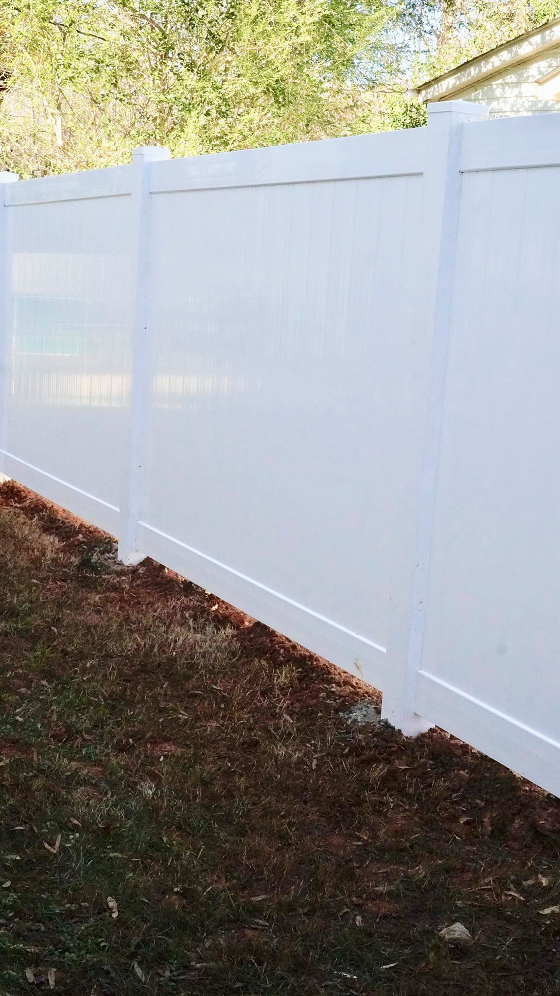 A white vinyl fence is sitting in the middle of a yard.