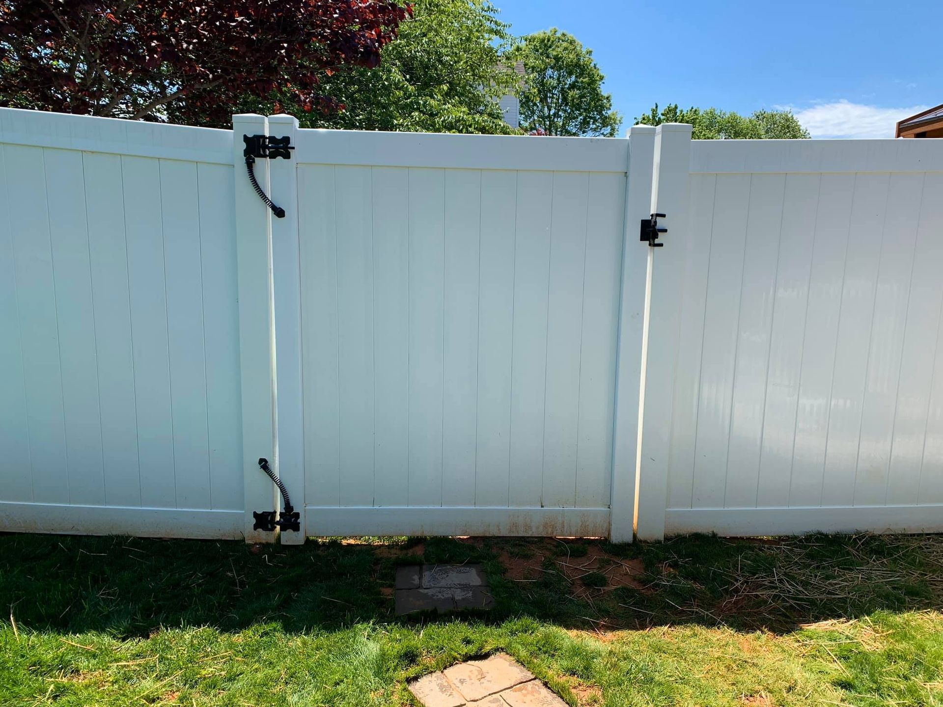 A white vinyl fence with a gate in the backyard.