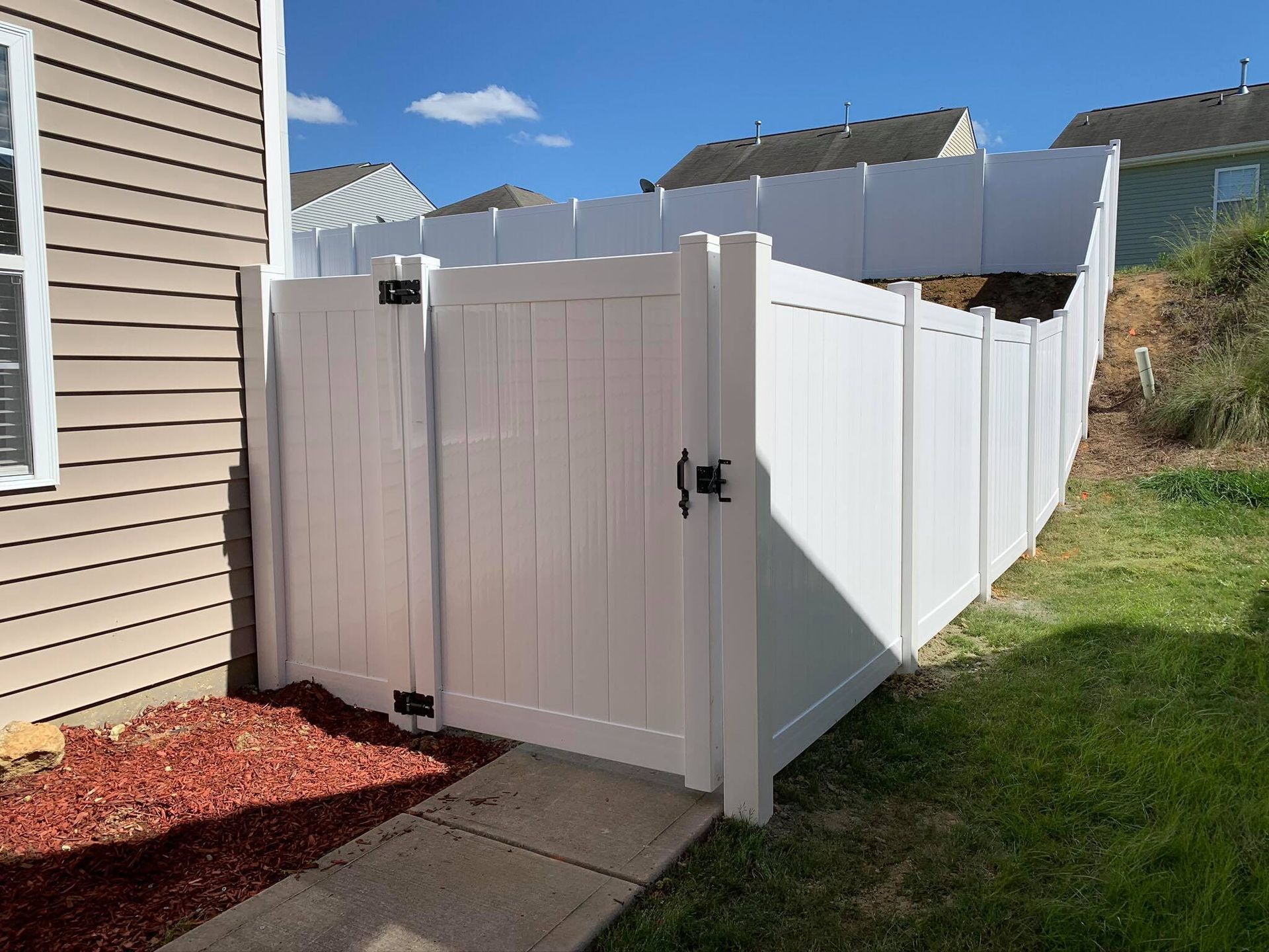 A white fence with a gate in front of a house.