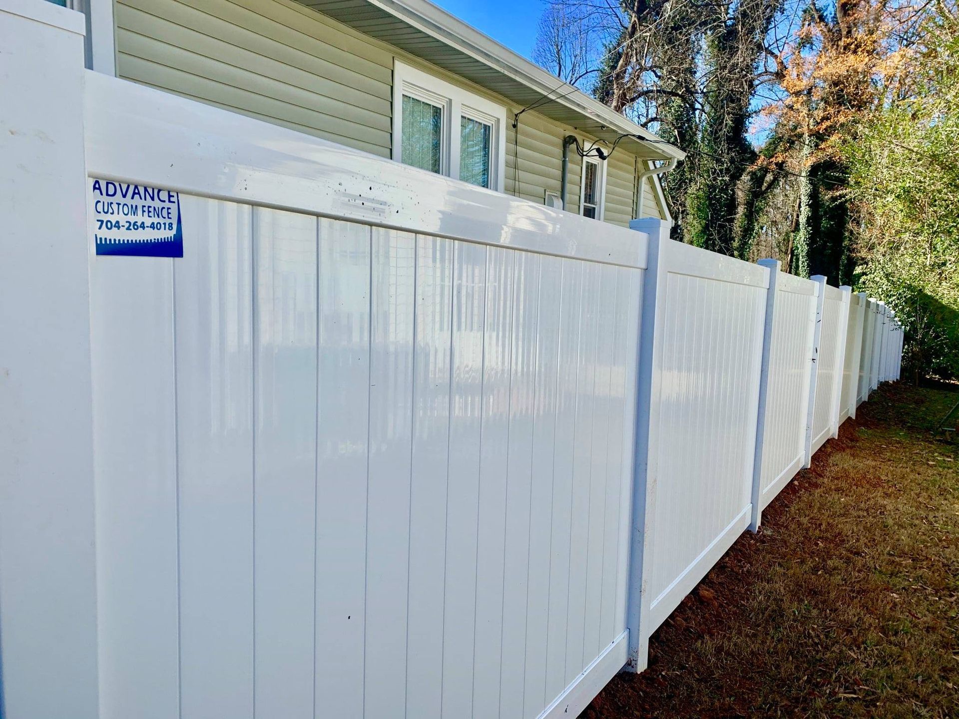 A white vinyl fence is sitting in front of a house.
