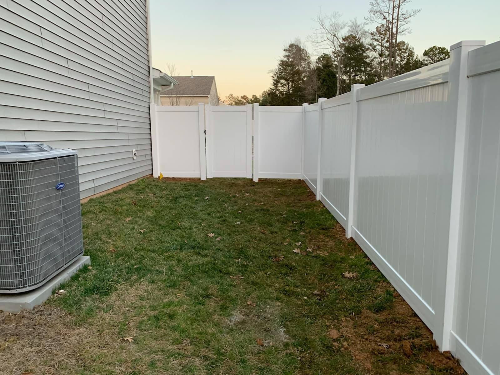There is a white fence in the backyard of a house.