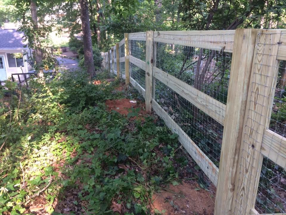 A wooden fence is surrounded by trees and bushes.