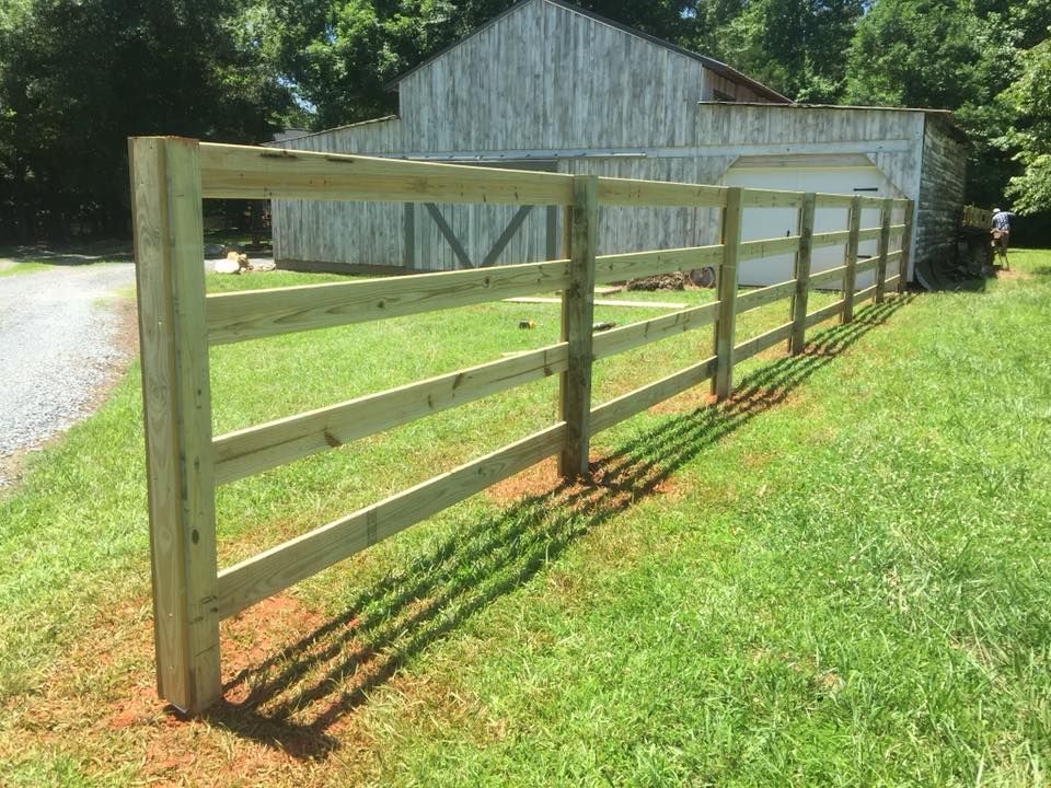 A wooden fence is sitting in the middle of a lush green field.