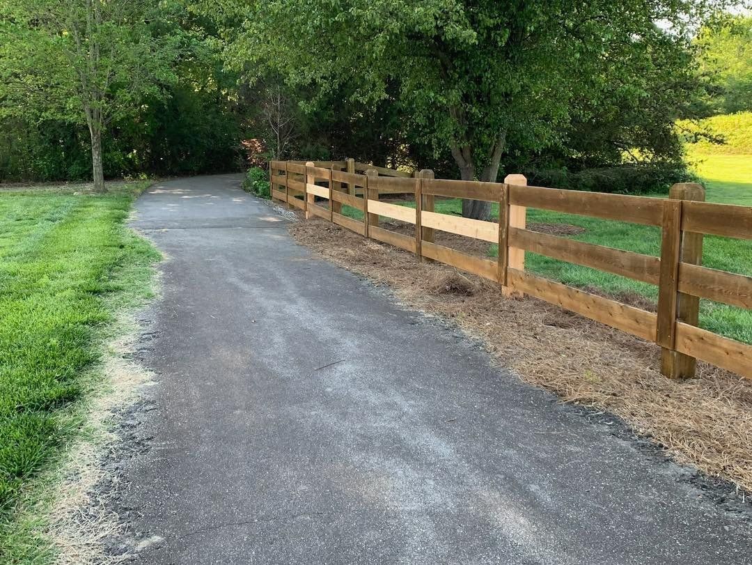 There is a wooden fence along the side of the road.