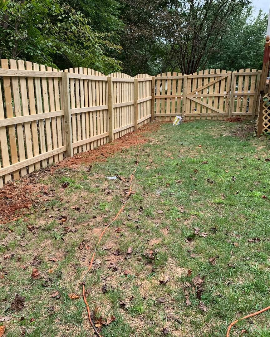 A wooden fence surrounds a lush green yard.