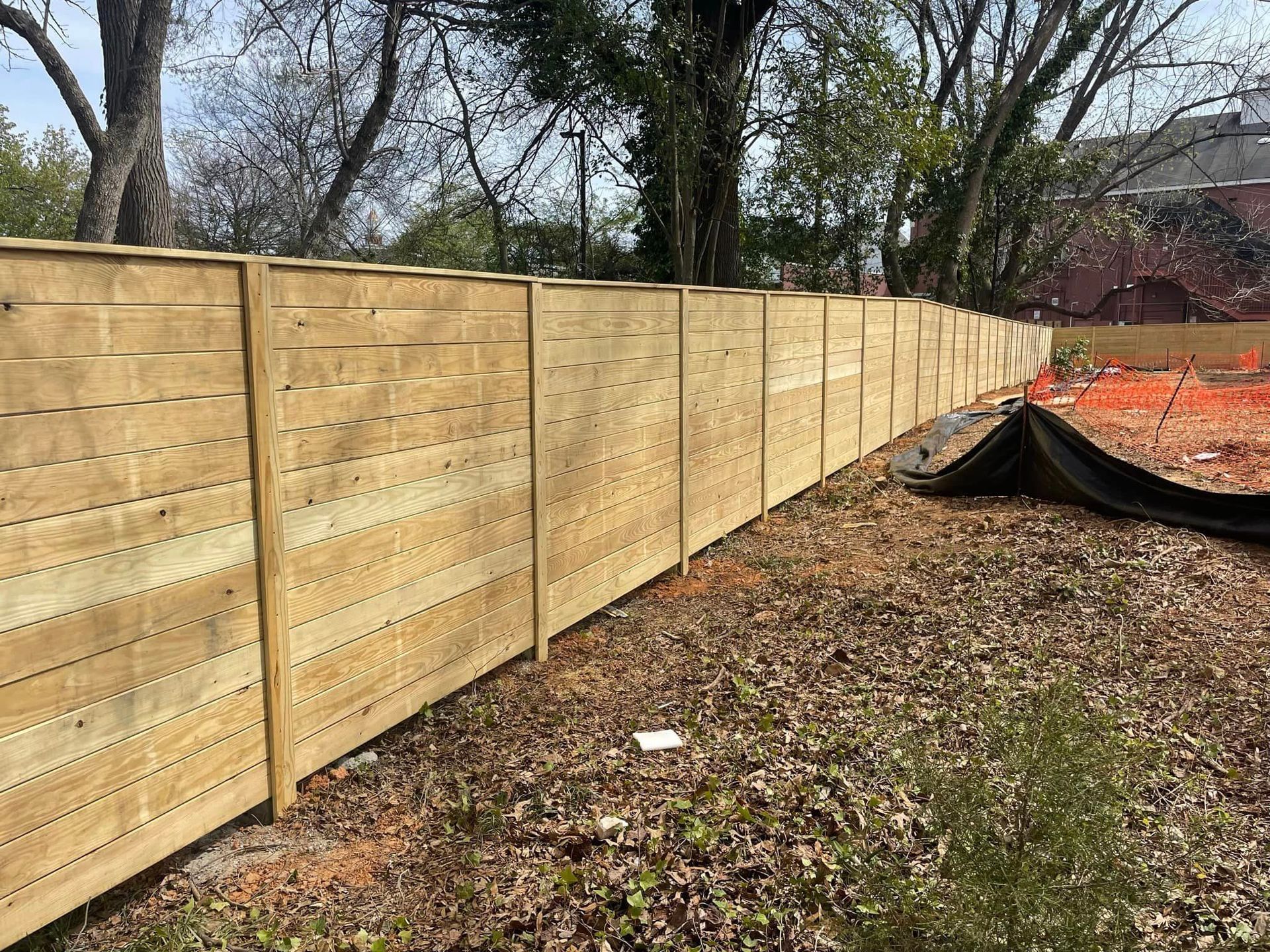 A wooden fence is sitting on top of a pile of leaves in a yard.