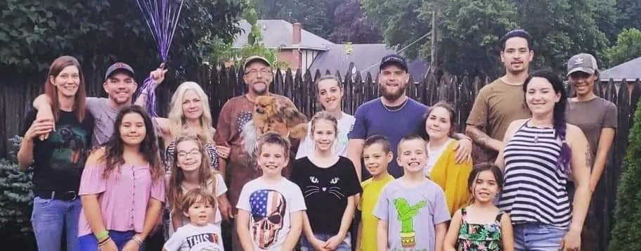 A large group of people smiling for a photo outside a home.