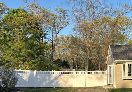 A large wooden deck with a white railing on the side of a house.