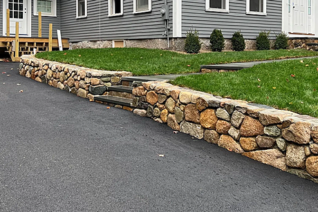 A stone wall with stairs leading up to a house.