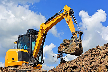 A yellow excavator is digging a pile of dirt on a construction site.
