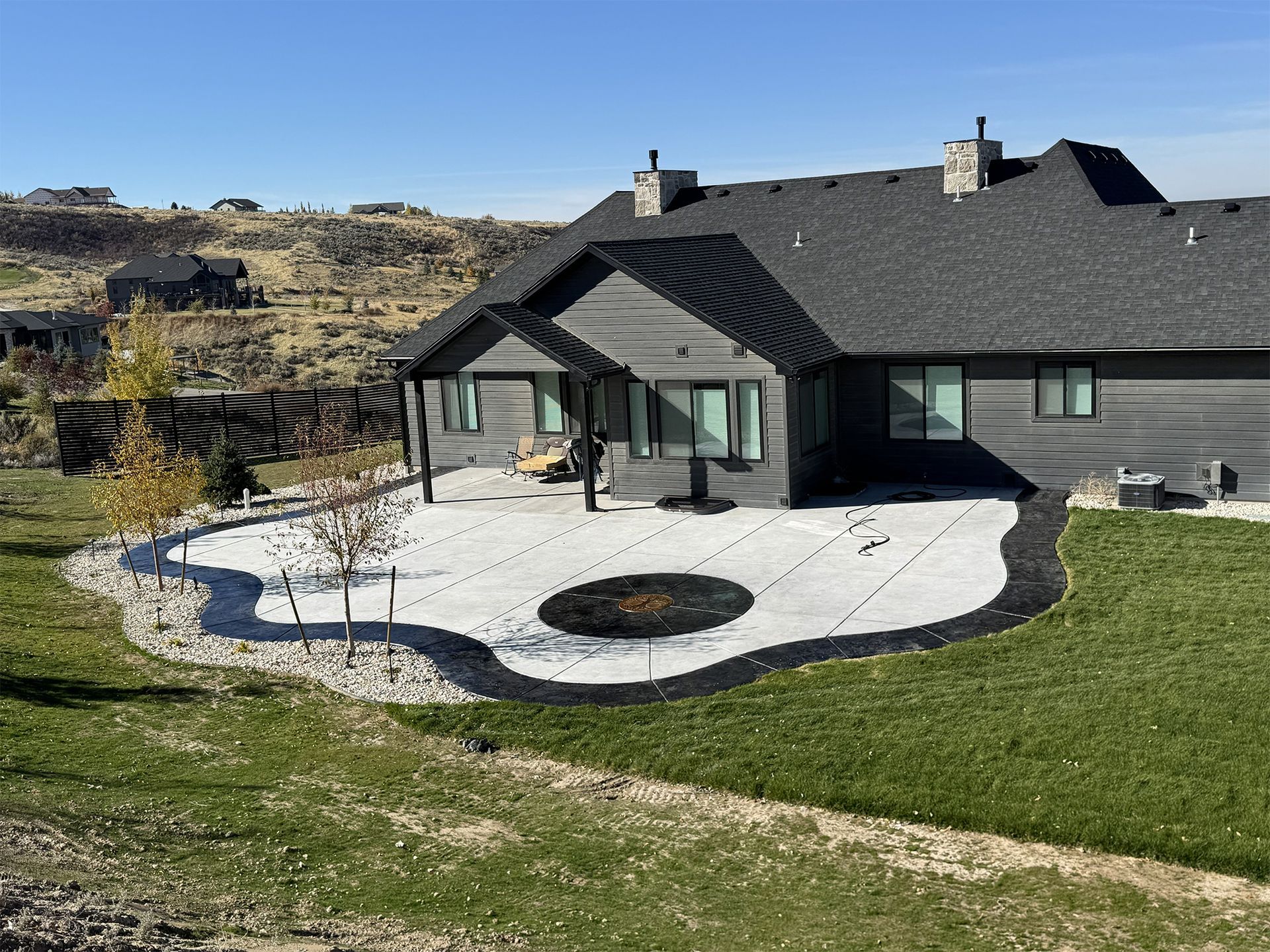 Gray house with patio, fire pit, and lawn.