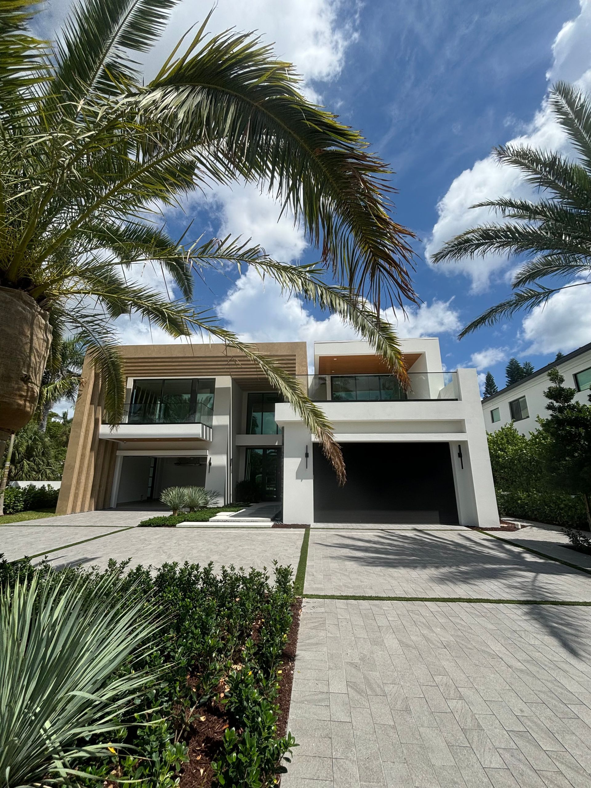 A modern house with a large garage and a palm tree in front of it.