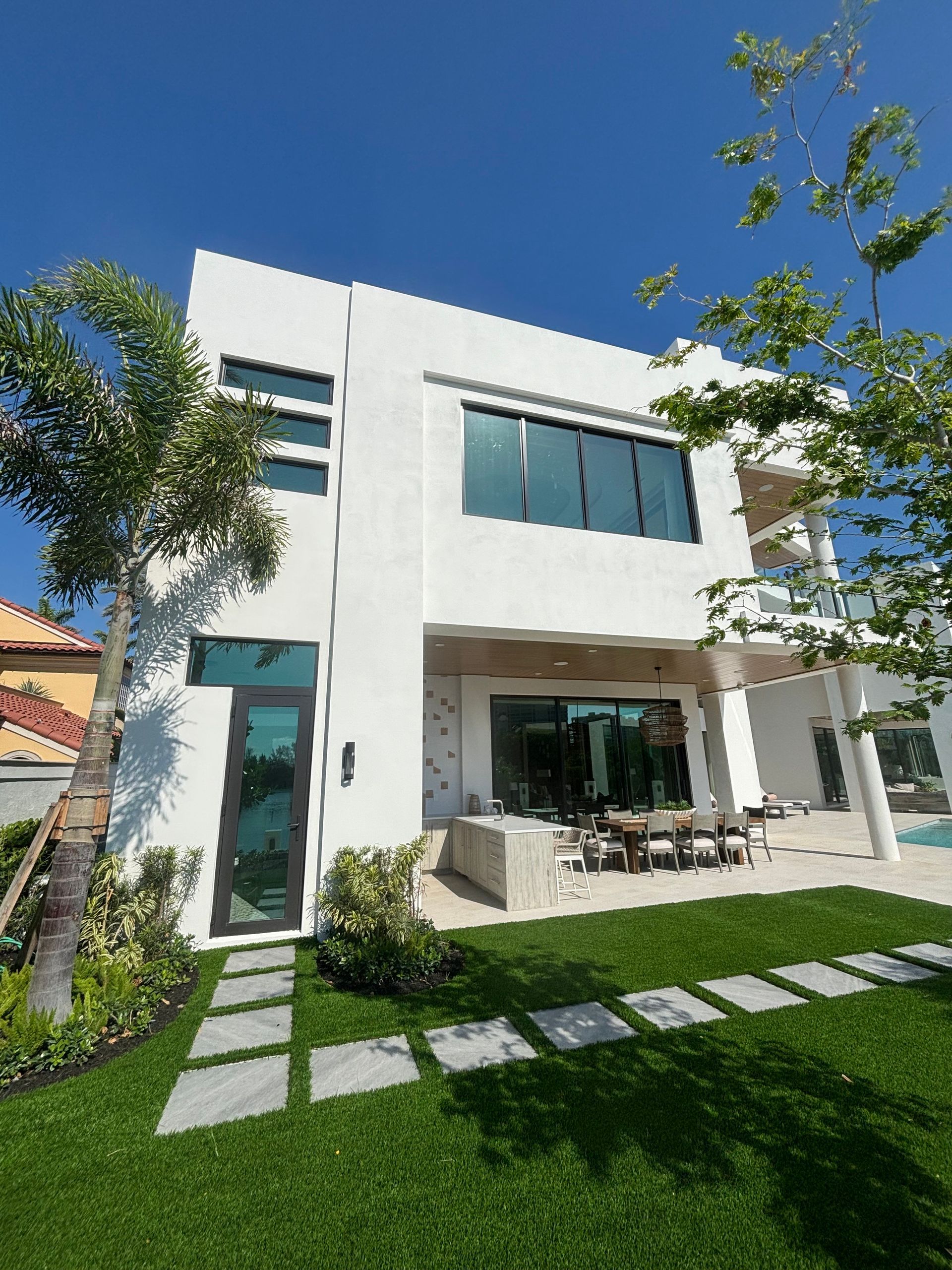 A large white house with a lot of windows is sitting on top of a lush green lawn.