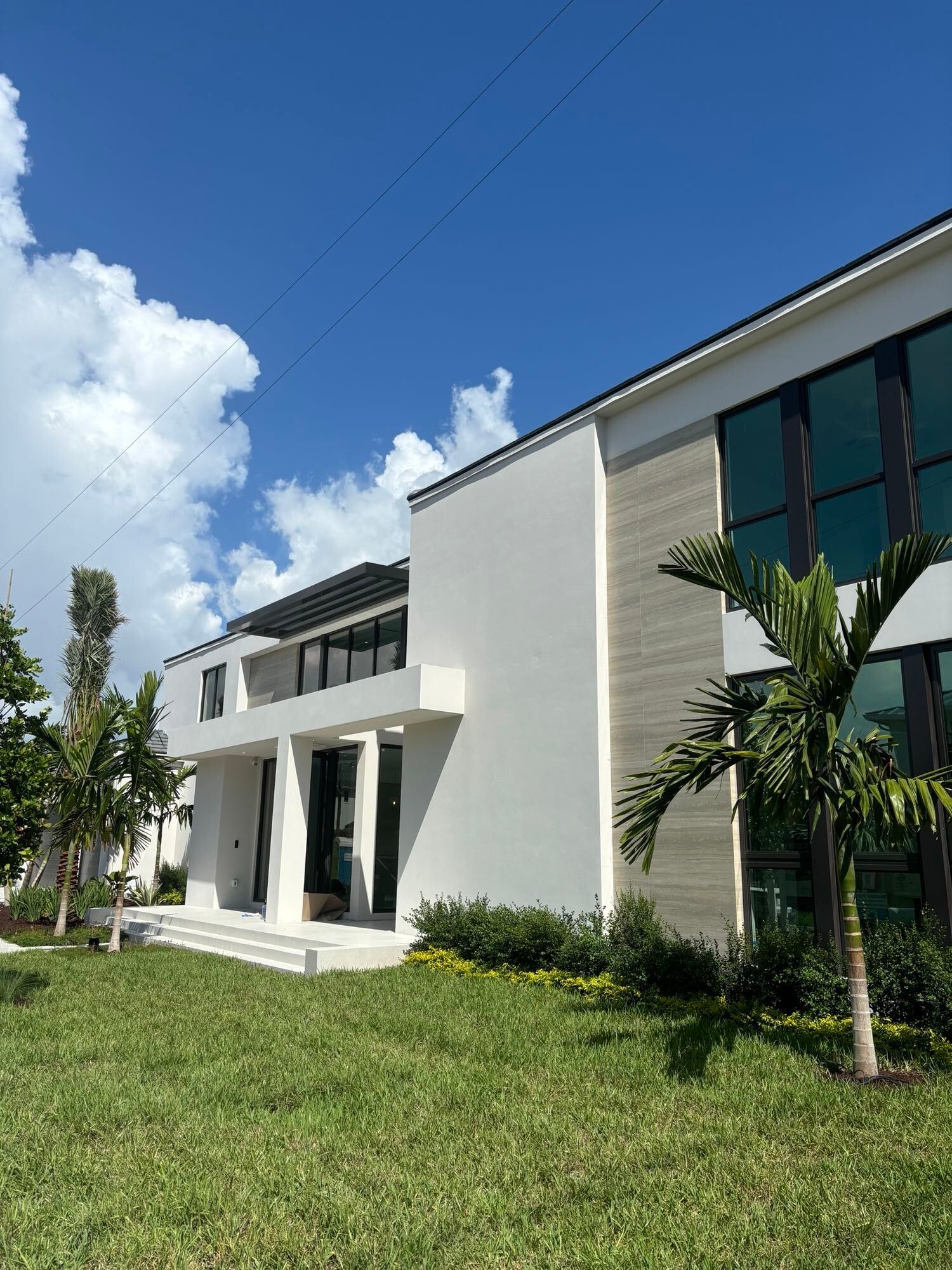 A large white building with a lot of windows is sitting on top of a lush green field.