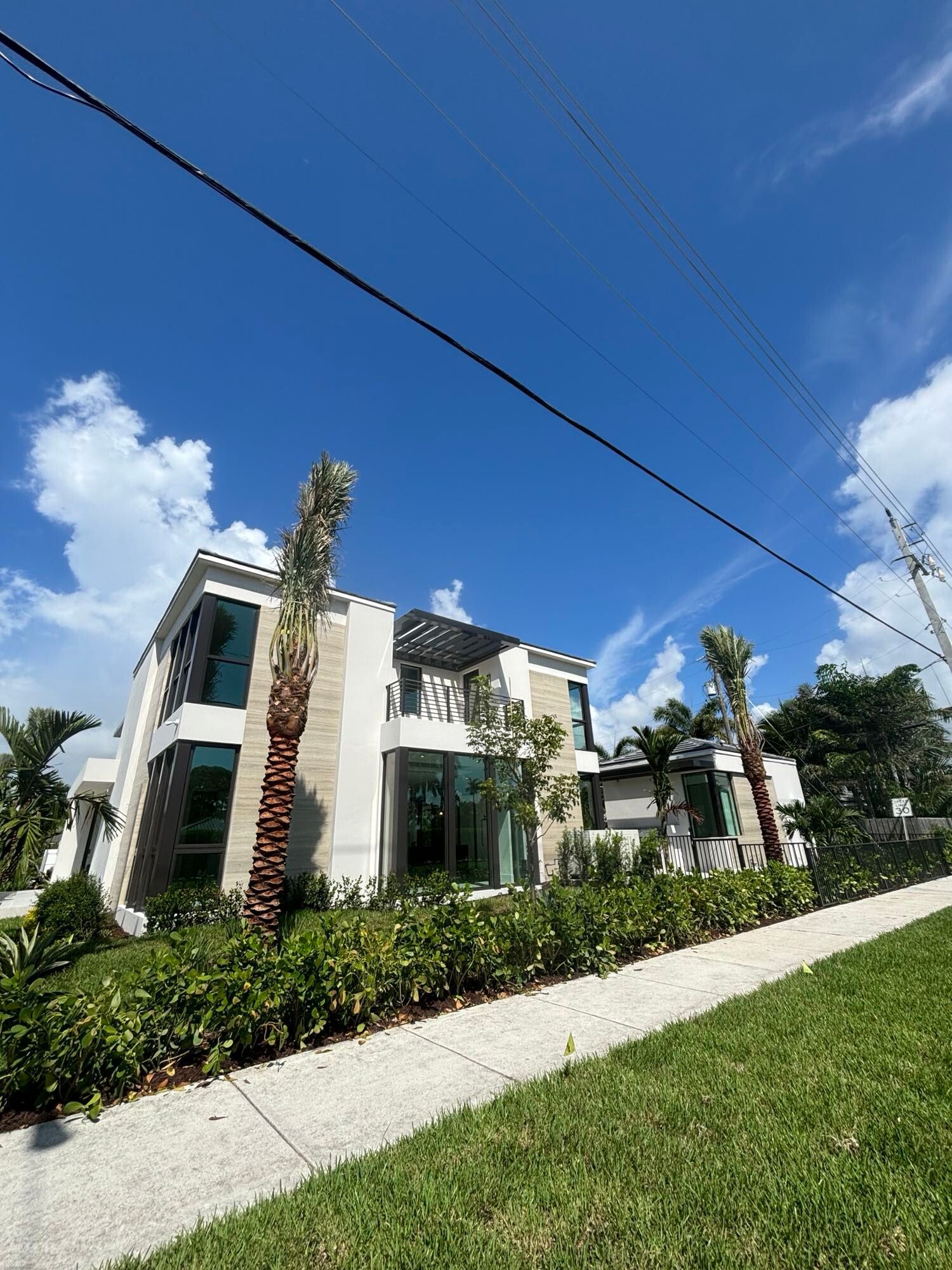 A large white house with palm trees in front of it on a sunny day.
