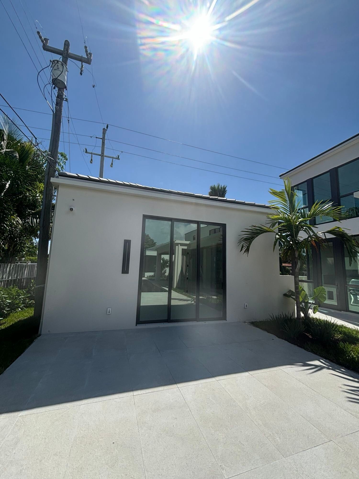 A small white house with sliding glass doors is sitting next to a large building.
