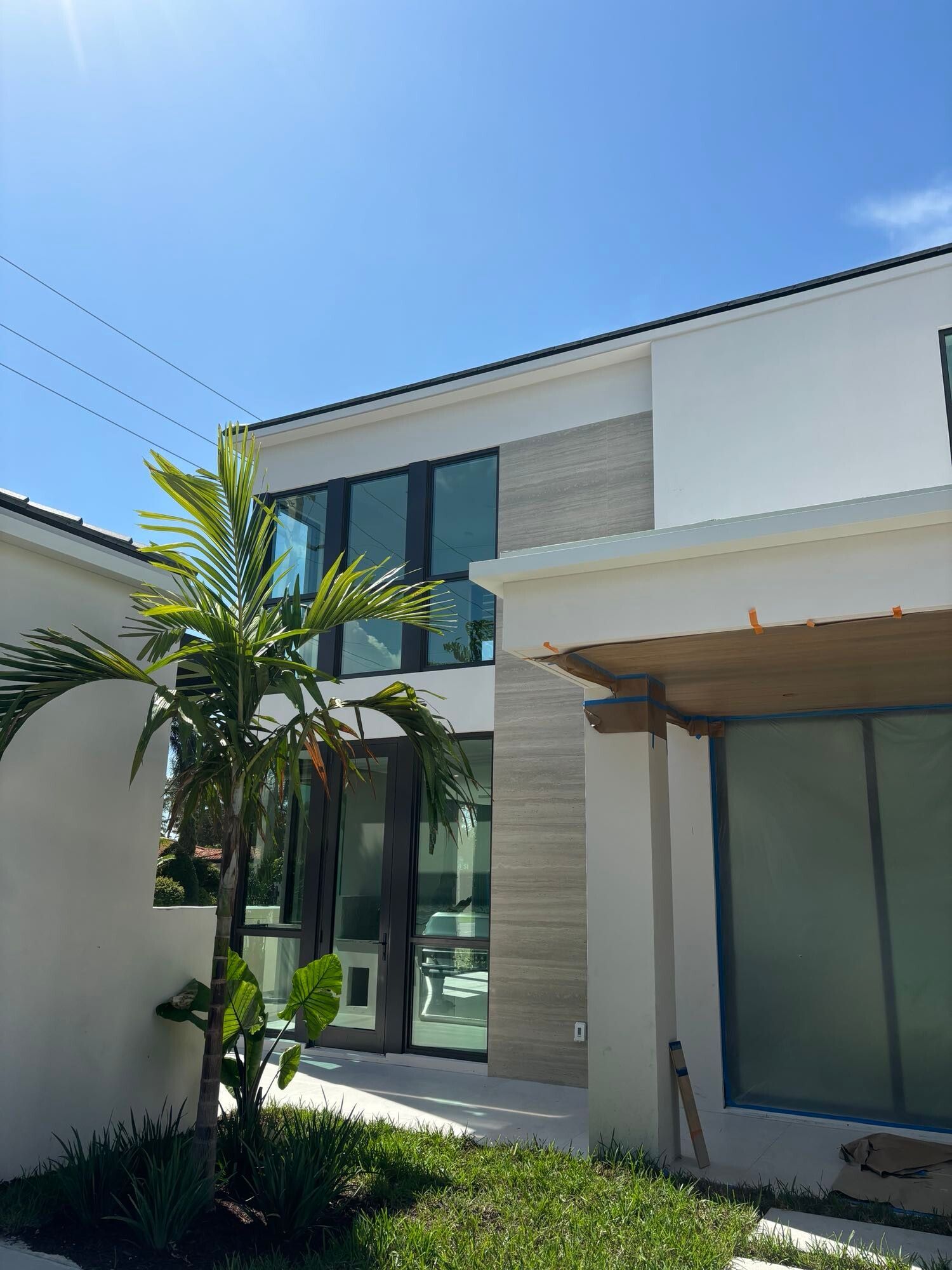 A large white house with a lot of windows and a palm tree in front of it.