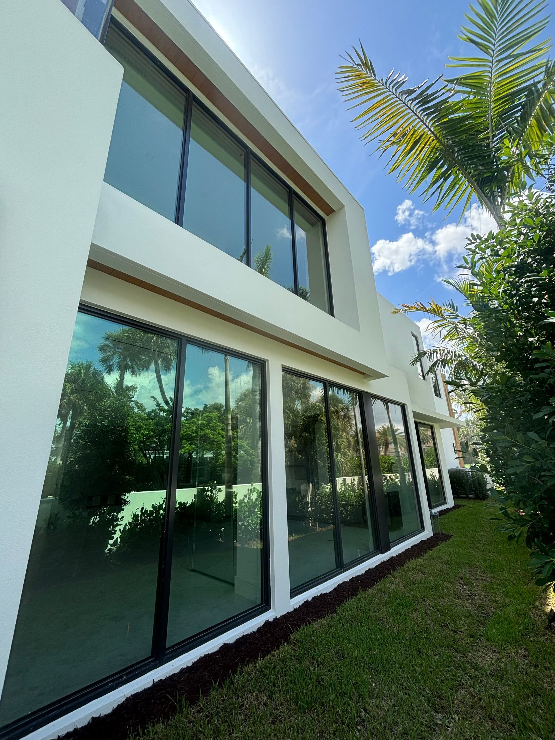 A large white house with a lot of windows and a lush green yard.