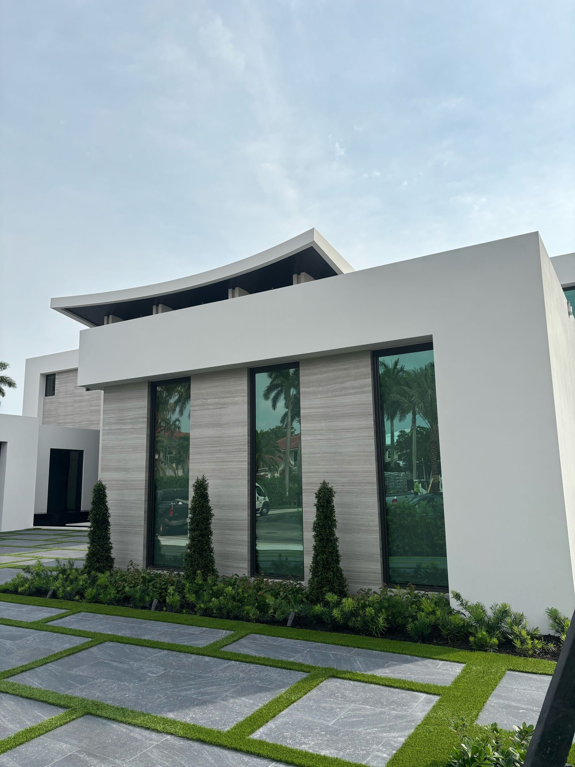 A white house with a lot of windows and a driveway in front of it.