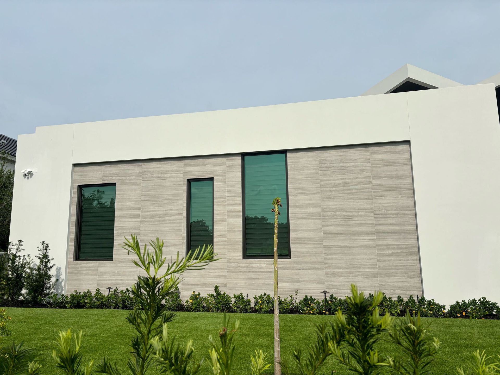 A large white house with a lot of windows and a lush green lawn in front of it.