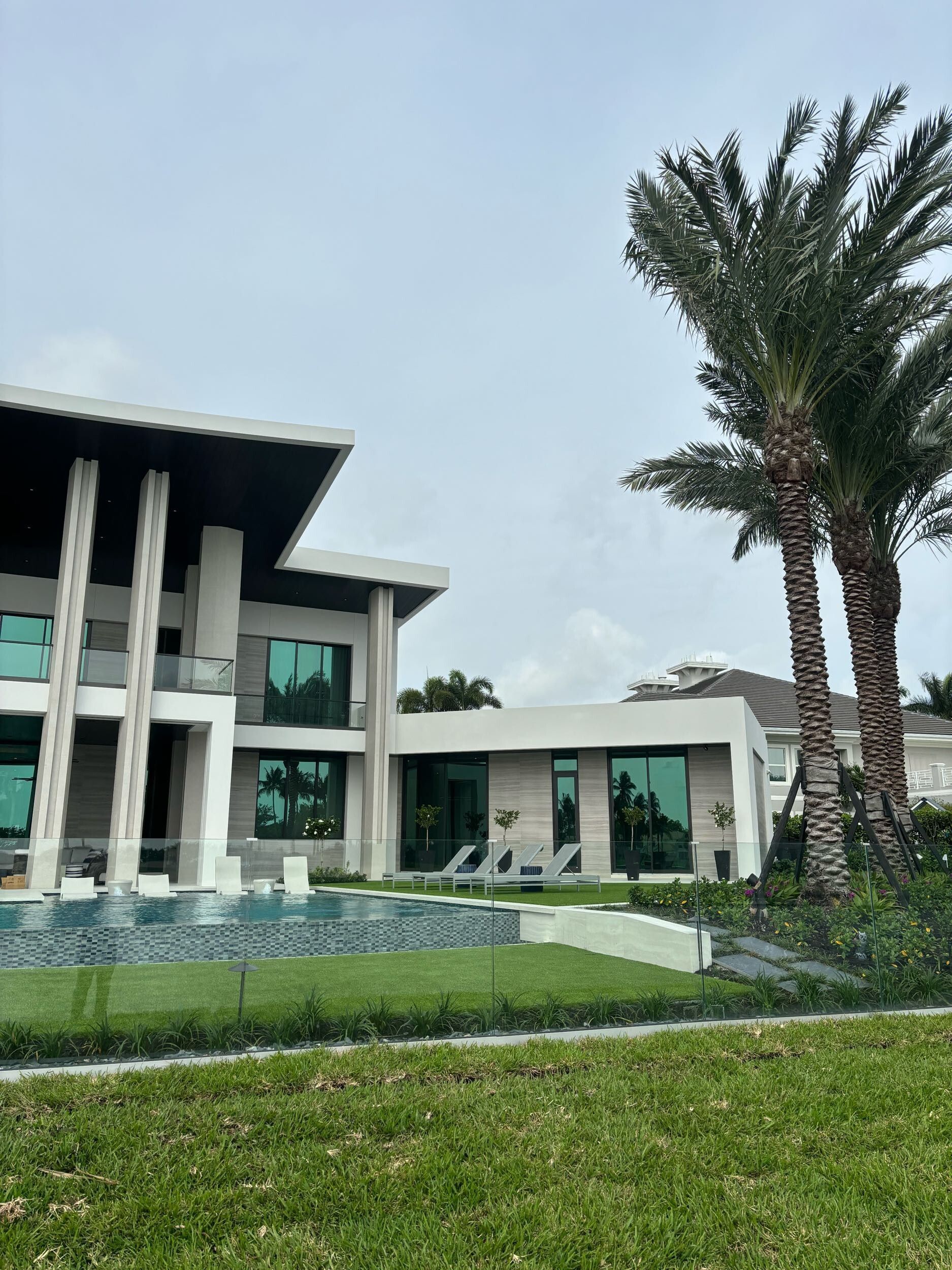 A large house with a pool and palm trees in front of it.