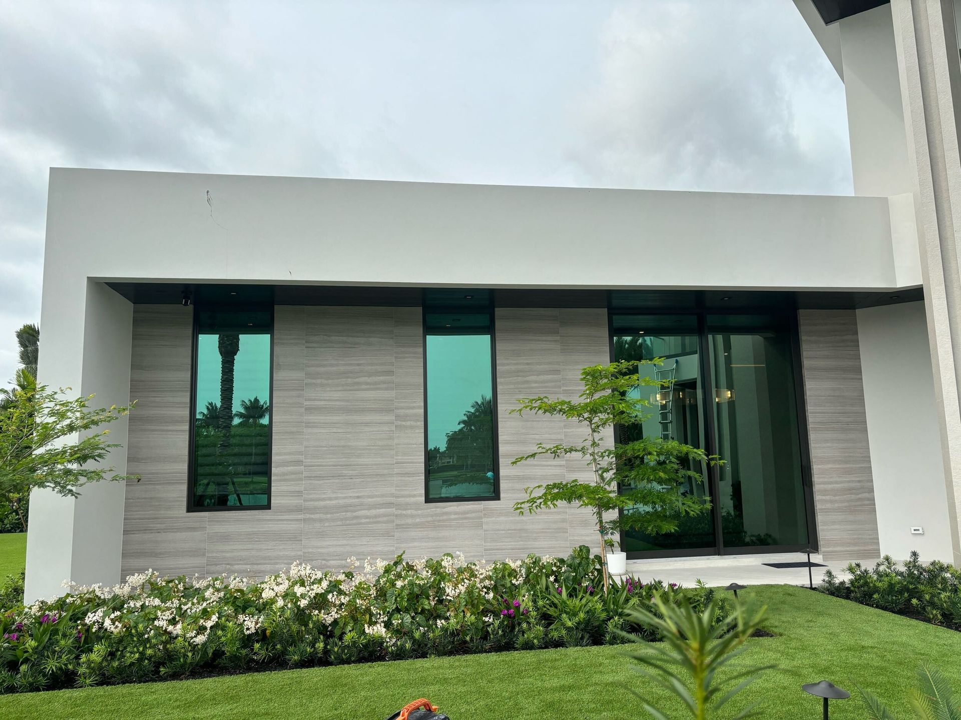 A modern house with a lot of windows and a lush green lawn in front of it.