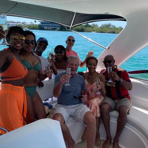 A group of people are sitting on a boat holding champagne glasses.