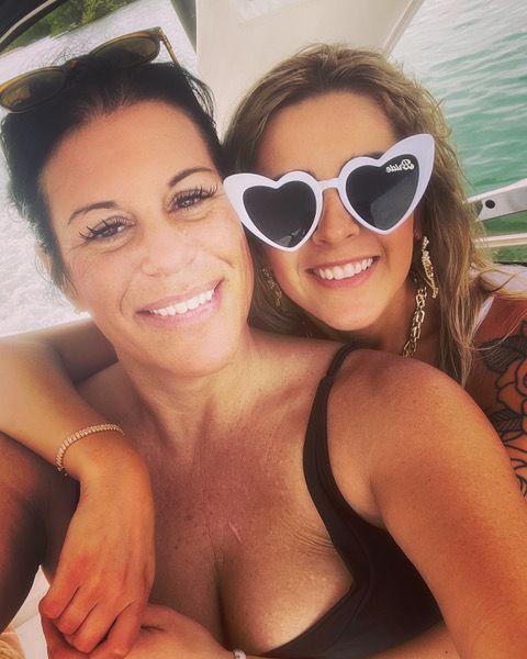 Two women wearing heart shaped sunglasses are posing for a picture.