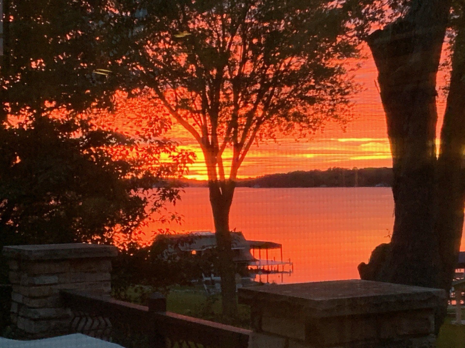 A sunset over a lake with a tree in the foreground