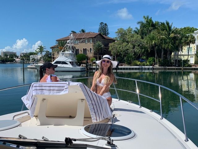 Two women are sitting on the front of a boat in the water.